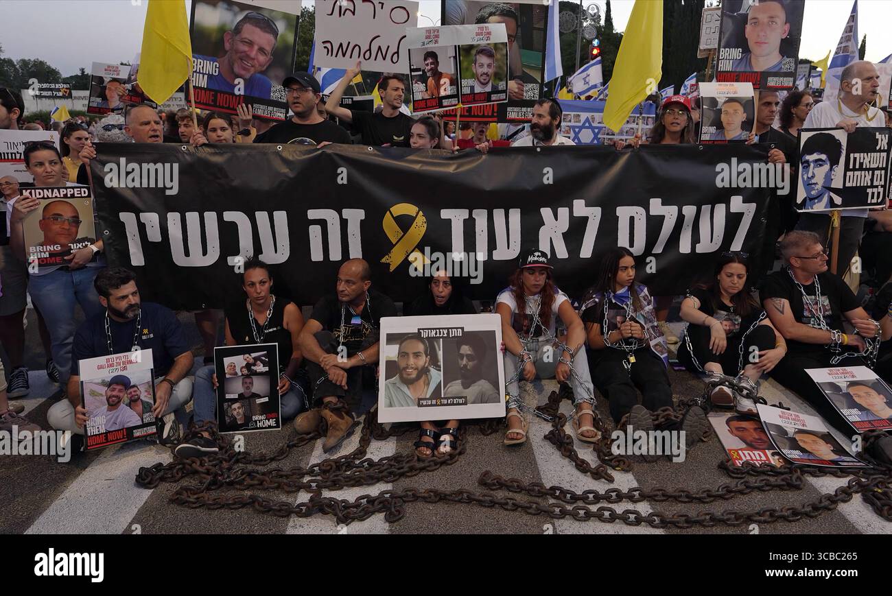 JÉRUSALEM - 7 AOÛT : Einav Zangauker (C), dont le fils Matan est retenu en otage à Gaza, est assis parmi des familles d'otages enchaînés et portant des pancartes portant des photographies d'otages lors d'une manifestation devant le bureau du premier ministre pendant que le cabinet de sécurité israélien se réunit pour décider s'il convient d'autoriser une prise de contrôle militaire complète de la bande de Gaza le 7 août 2025 à Jérusalem. Israël Banque D'Images JÉRUSALEM - 7 AOÛT : Einav Zangauker (C), dont le fils Matan est retenu en otage à Gaza, est assis parmi des familles d'otages enchaînés et portant des pancartes portant des photographies d'otages lors d'une manifestation devant le bureau du premier ministre pendant que le cabinet de sécurité israélien se réunit pour décider s'il convient d'autoriser une prise de contrôle militaire complète de la bande de Gaza le 7 août 2025 à Jérusalem. Israël Banque D'Images