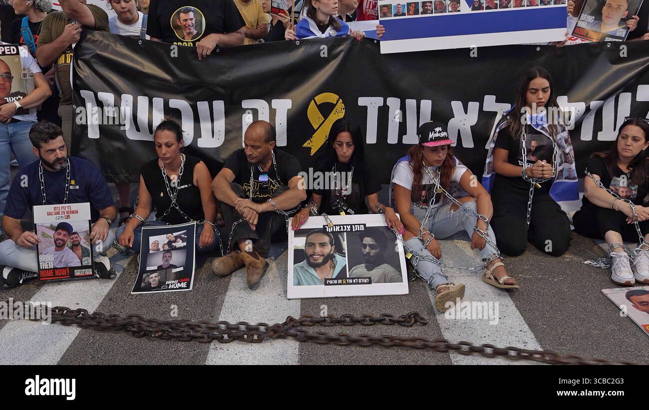 JÉRUSALEM - 7 AOÛT : Einav Zangauker (C), dont le fils Matan est retenu en otage à Gaza, est assis parmi des familles d'otages enchaînés et portant des pancartes portant des photographies d'otages lors d'une manifestation devant le bureau du premier ministre pendant que le cabinet de sécurité israélien se réunit pour décider s'il convient d'autoriser une prise de contrôle militaire complète de la bande de Gaza le 7 août 2025 à Jérusalem. Israël Banque D'Images JÉRUSALEM - 7 AOÛT : Einav Zangauker (C), dont le fils Matan est retenu en otage à Gaza, est assis parmi des familles d'otages enchaînés et portant des pancartes portant des photographies d'otages lors d'une manifestation devant le bureau du premier ministre pendant que le cabinet de sécurité israélien se réunit pour décider s'il convient d'autoriser une prise de contrôle militaire complète de la bande de Gaza le 7 août 2025 à Jérusalem. Israël Banque D'Images