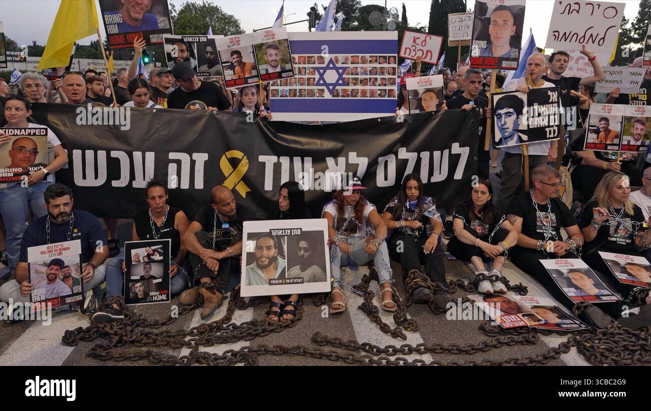 JÉRUSALEM - 7 AOÛT : Einav Zangauker (C), dont le fils Matan est retenu en otage à Gaza, est assis parmi des familles d'otages enchaînés et portant des pancartes portant des photographies d'otages lors d'une manifestation devant le bureau du premier ministre pendant que le cabinet de sécurité israélien se réunit pour décider s'il convient d'autoriser une prise de contrôle militaire complète de la bande de Gaza le 7 août 2025 à Jérusalem. Israël Banque D'Images JÉRUSALEM - 7 AOÛT : Einav Zangauker (C), dont le fils Matan est retenu en otage à Gaza, est assis parmi des familles d'otages enchaînés et portant des pancartes portant des photographies d'otages lors d'une manifestation devant le bureau du premier ministre pendant que le cabinet de sécurité israélien se réunit pour décider s'il convient d'autoriser une prise de contrôle militaire complète de la bande de Gaza le 7 août 2025 à Jérusalem. Israël Banque D'Images