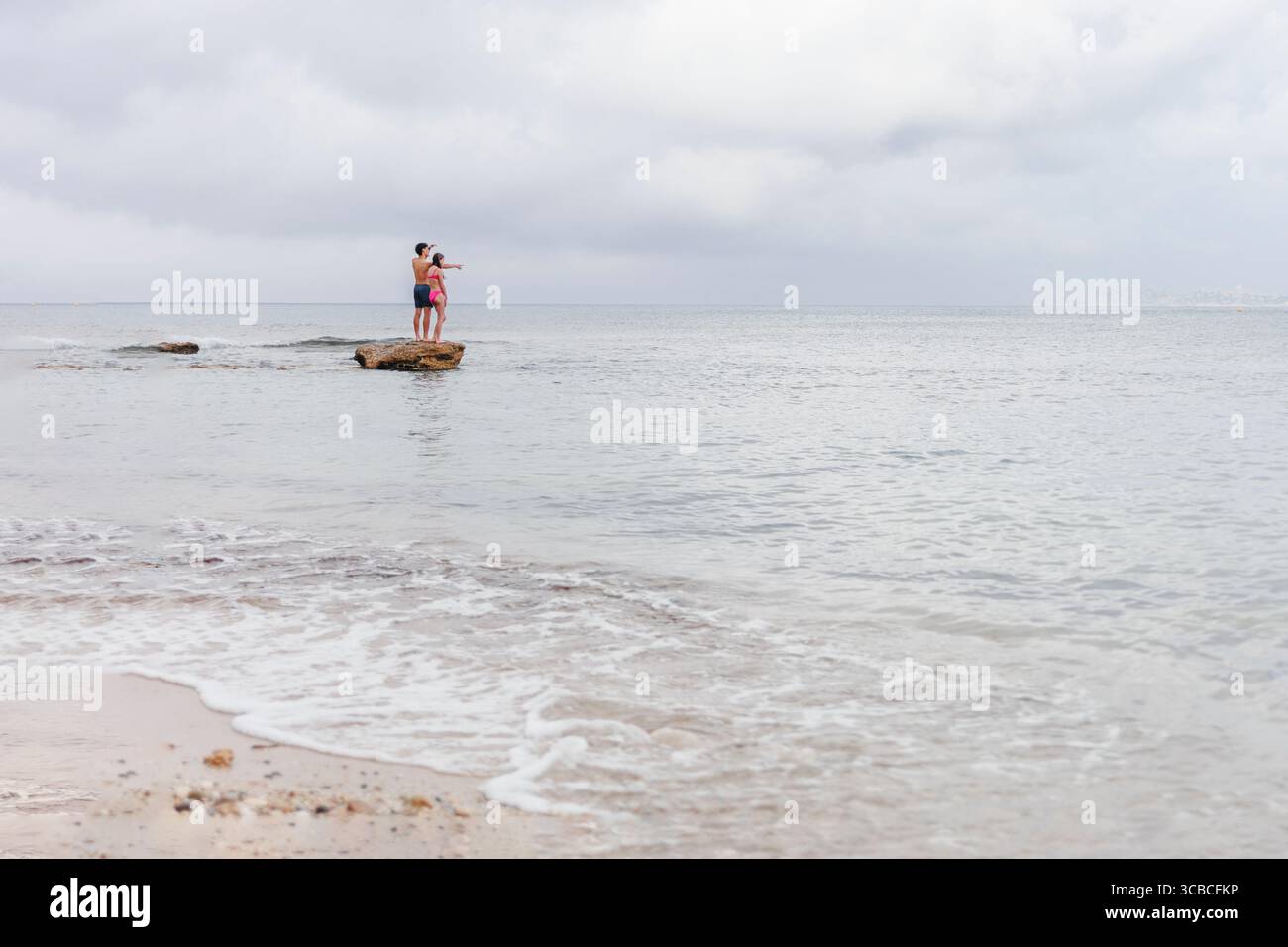 Deux adolescents se tiennent sur le rocher au bord de la mer regardant à l'ocea Banque D'Images