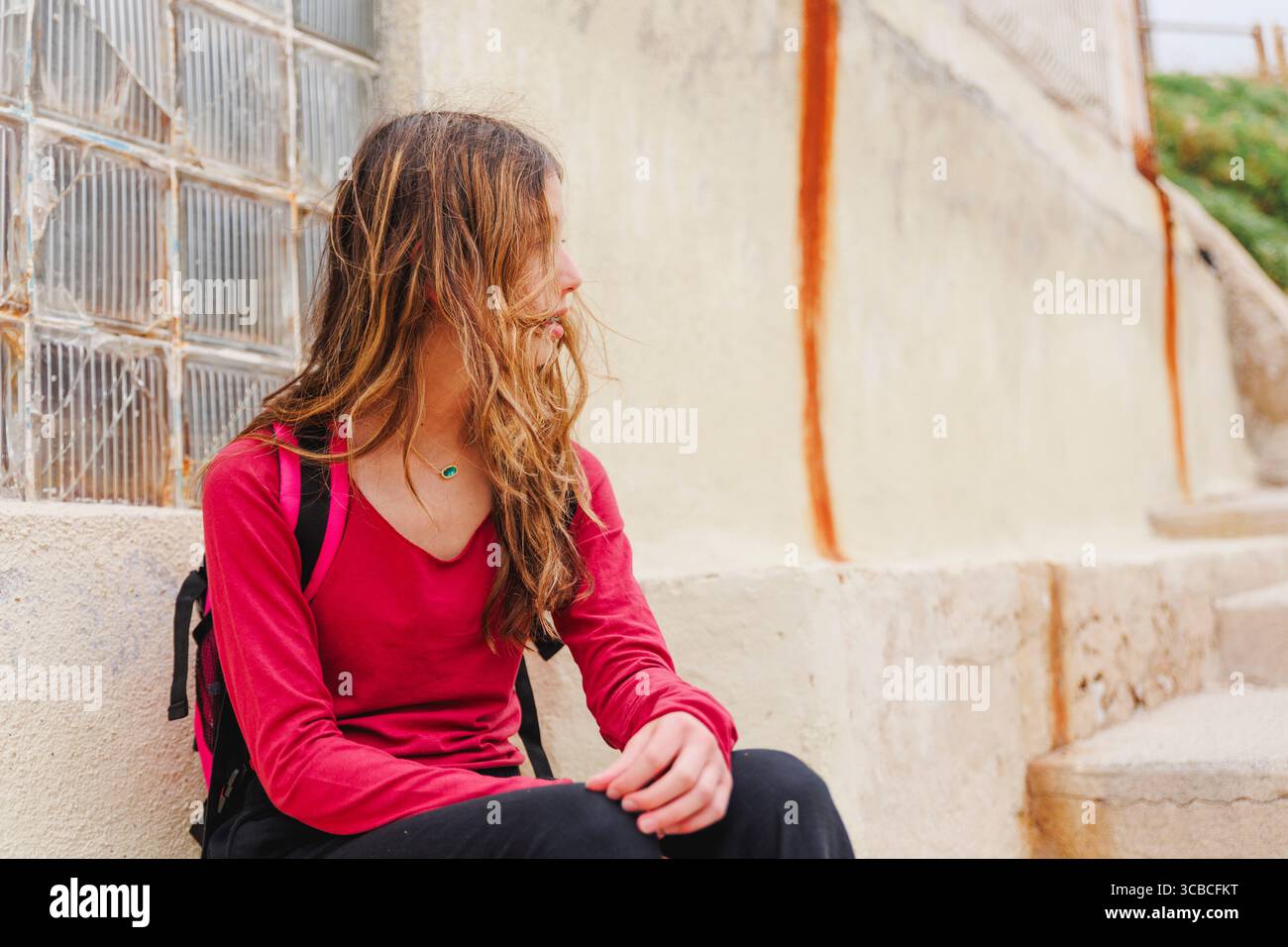 Vue latérale de la fille avec de longs cheveux soufflés par le vent et sac à dos Banque D'Images