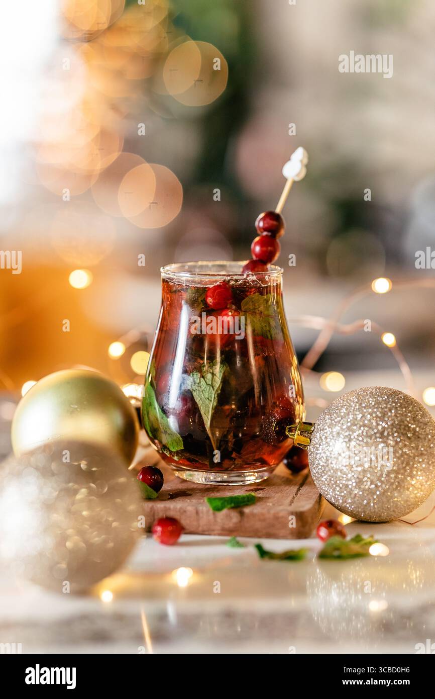 Sangria des fêtes avec garniture de canneberge, ornements et lumières. Banque D'Images