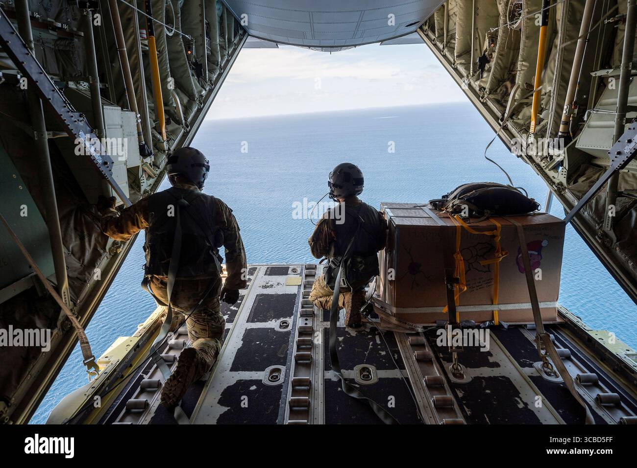 Le 5 décembre 2023, atoll de Satawan, État de Chuuk, États fédérés de Micronésie : Joseph Snell, aviateur senior de l'US Air Force, à gauche, et le Sgt d'état-major Matthew Muravez, maîtres de chargement du 36e escadron expéditionnaire aérien observent des faisceaux humanitaires parachutés vers une lagune depuis un avion C-130J Super Hercules de l'US Air Force pendant l'opération Christmas Drop, le 5 décembre 2023 dans l'atoll de Satawan, Micronésie. L’opération Christmas Drop est la plus ancienne mission humanitaire et de secours en cas de catastrophe, livrant 71 000 livres de nourriture, de cadeaux et de fournitures pour aider les communautés insulaires éloignées du Pacifique Sud. (Crédit image : © Banque D'Images