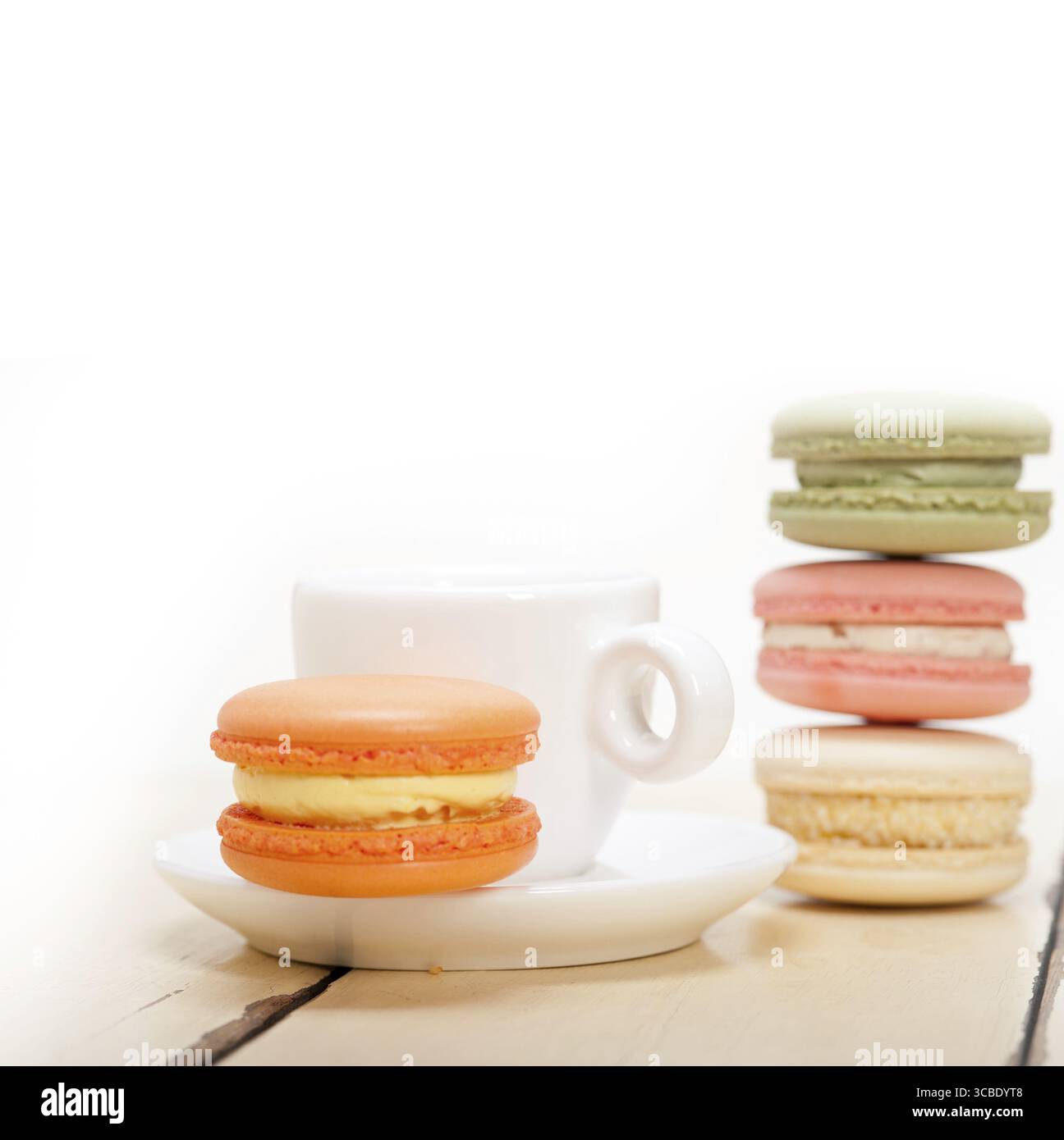 Macarons colorés avec café expresso sur table en bois blanc Banque D'Images