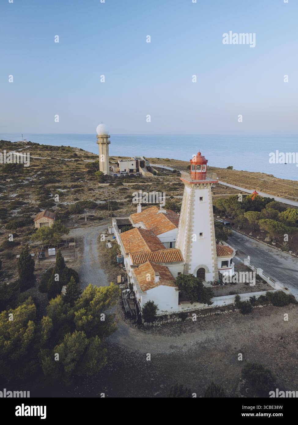 Vue aérienne du phare blanc éclatant avec son chapeau rouge vif se dresse sentinelle contre la mer bleu profond, un phare d'espoir, Leucate, Occitanie, France. Banque D'Images