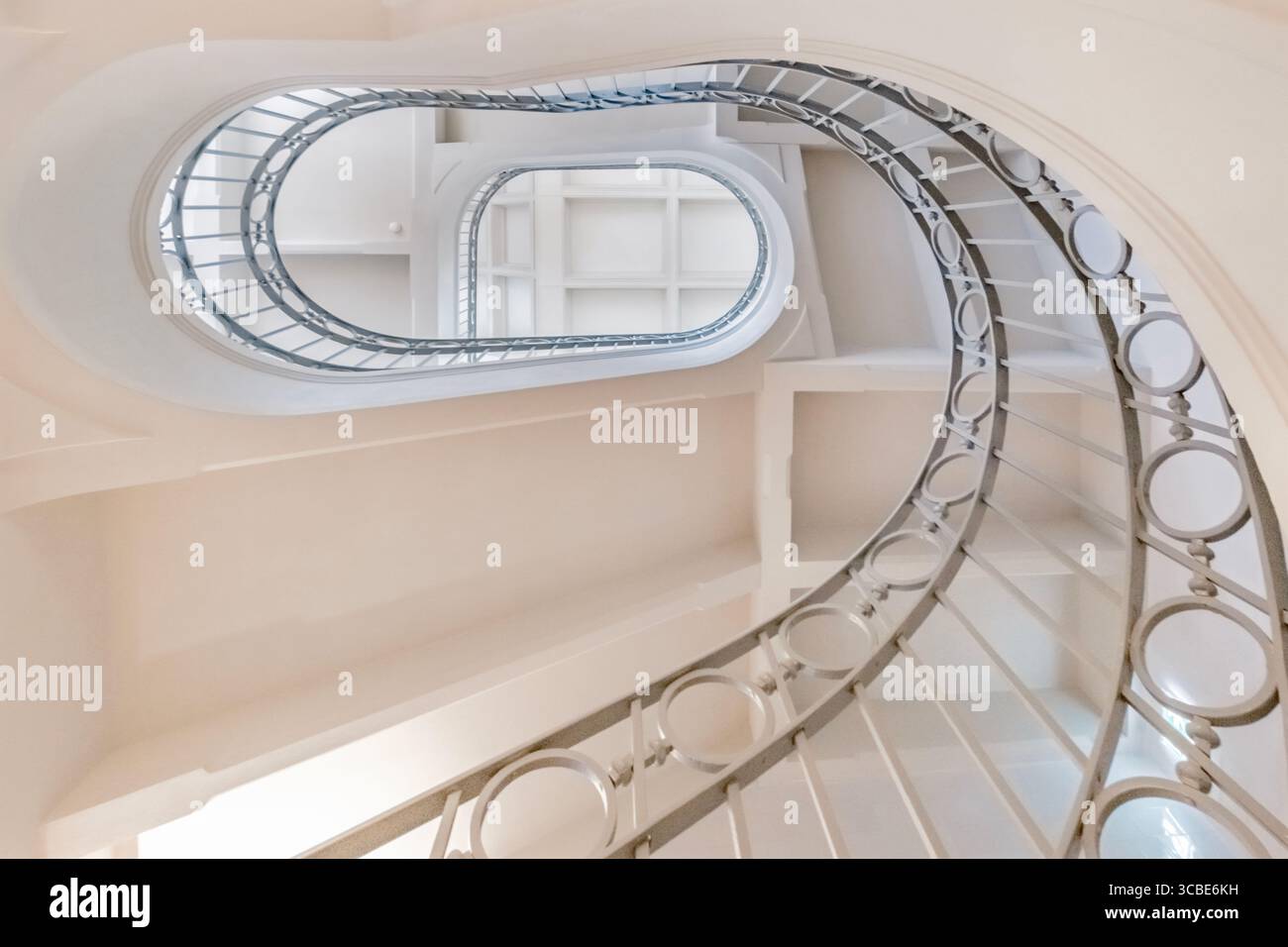 Élégant escalier en spirale avec garde-corps en métal orné dans un bâtiment classique. Beauté architecturale, étapes sinueuses, design d'intérieur, motif géométrique Banque D'Images