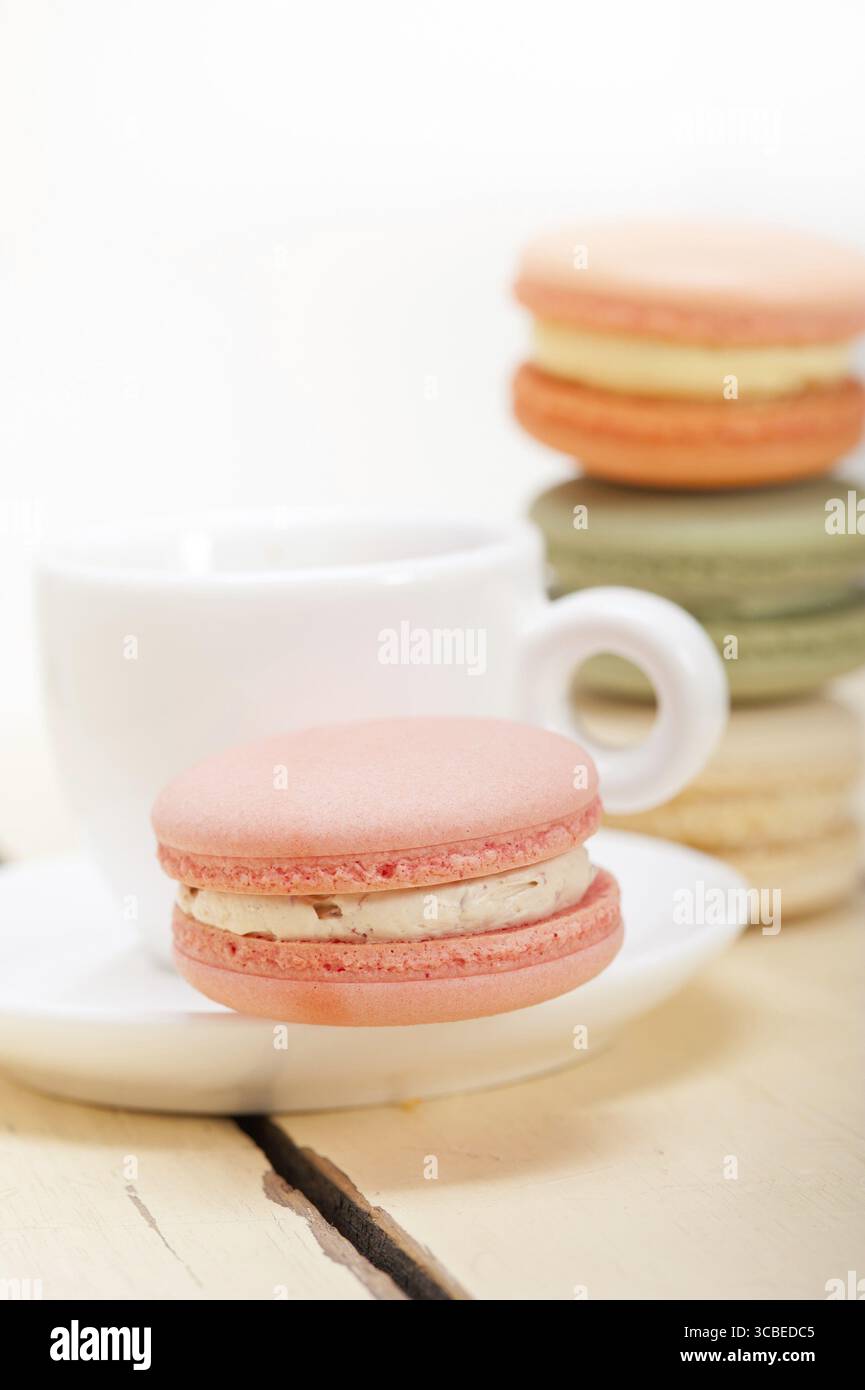 Macarons colorés avec café expresso sur table en bois blanc Banque D'Images