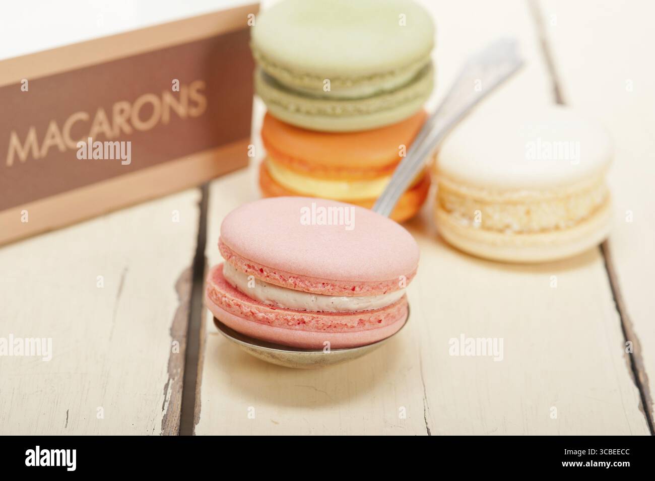 Macarons français colorés sur une table en bois rustique blanc Banque D'Images