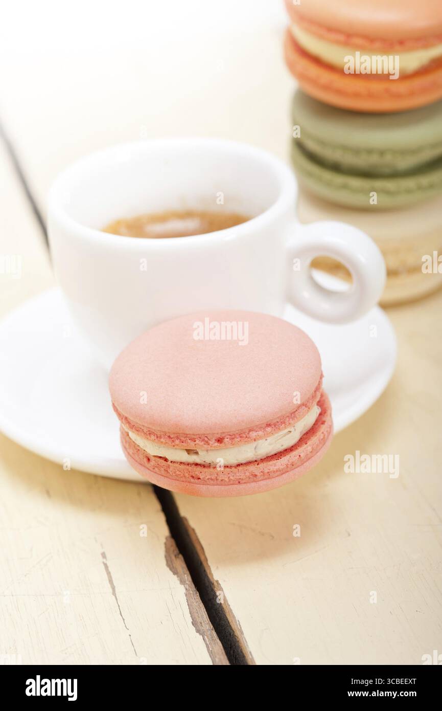 Macarons colorés avec café expresso sur table en bois blanc Banque D'Images