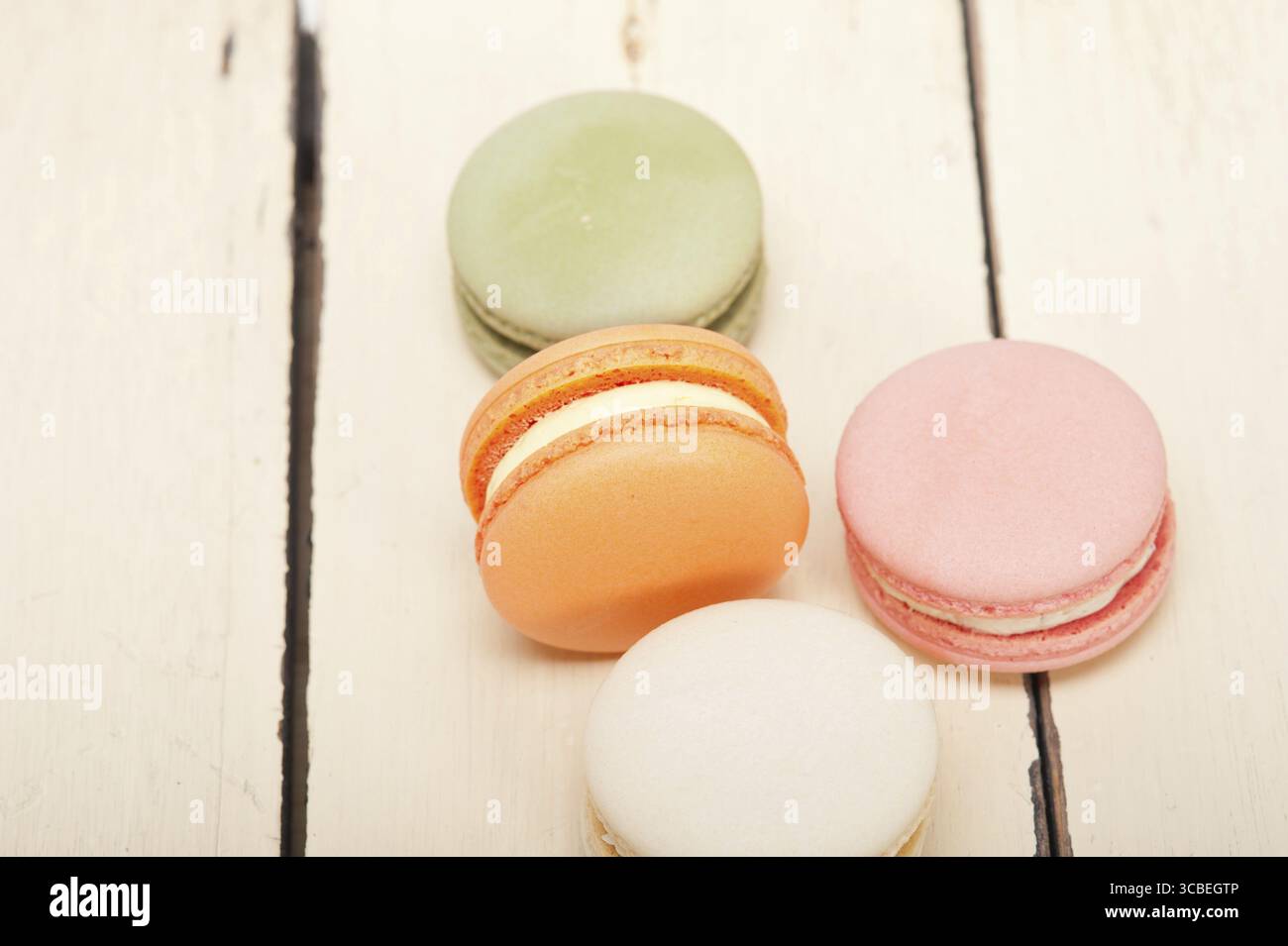 Macarons français colorés sur une table en bois rustique blanc Banque D'Images