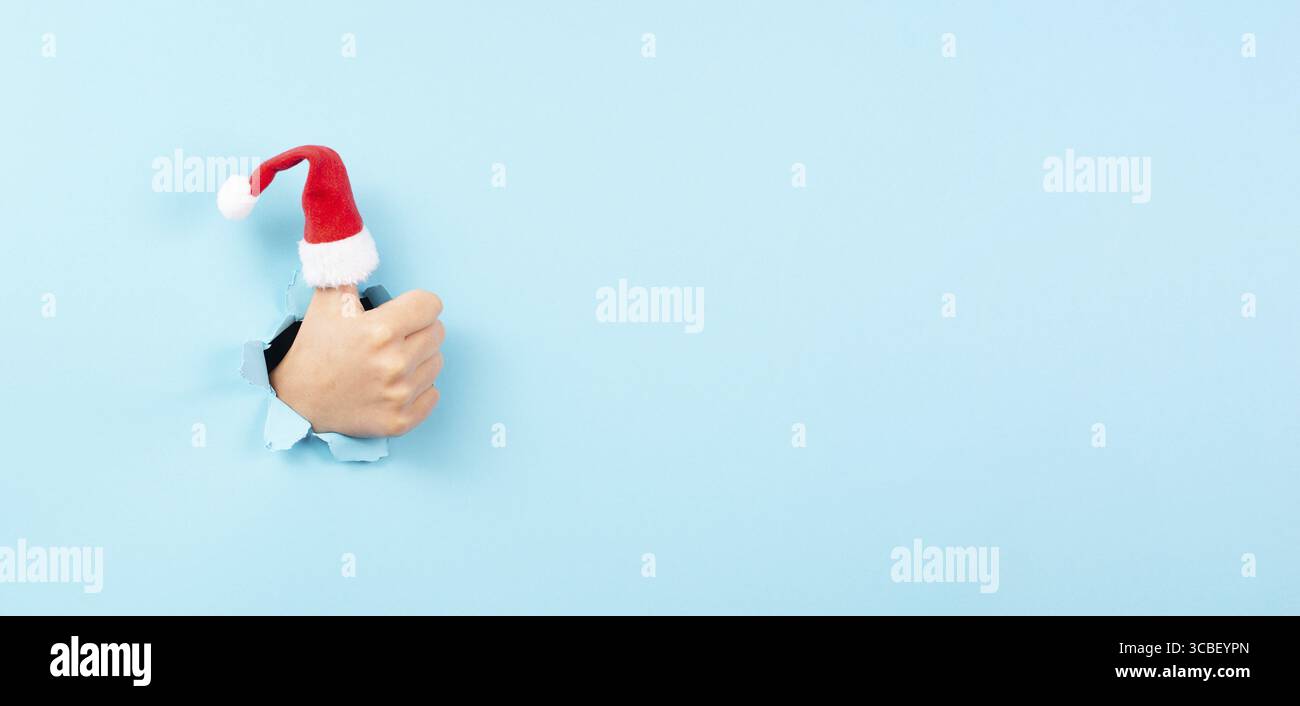 Pouce vers le haut, chapeau du Père Noël, vacances de Noël, geste positif de la main, optimisme et émotion, saison d'hiver Banque D'Images