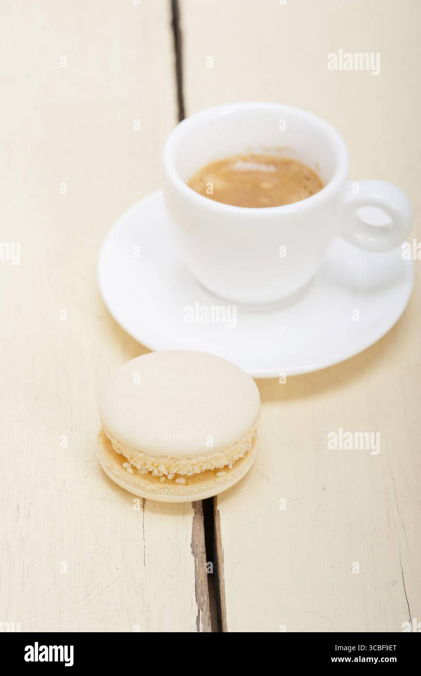 Macarons colorés avec café expresso sur table en bois blanc Banque D'Images