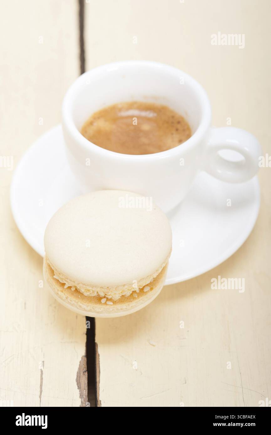 Macarons colorés avec café expresso sur table en bois blanc Banque D'Images