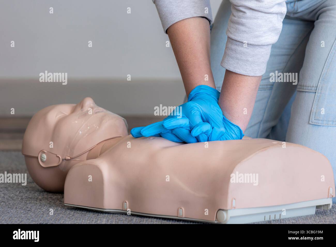 Gros plan des mains d'une instructrice de secourisme féminine démontrant la posture et la position correctes de la main pour administrer des compressions thoraciques sur un Basic Banque D'Images