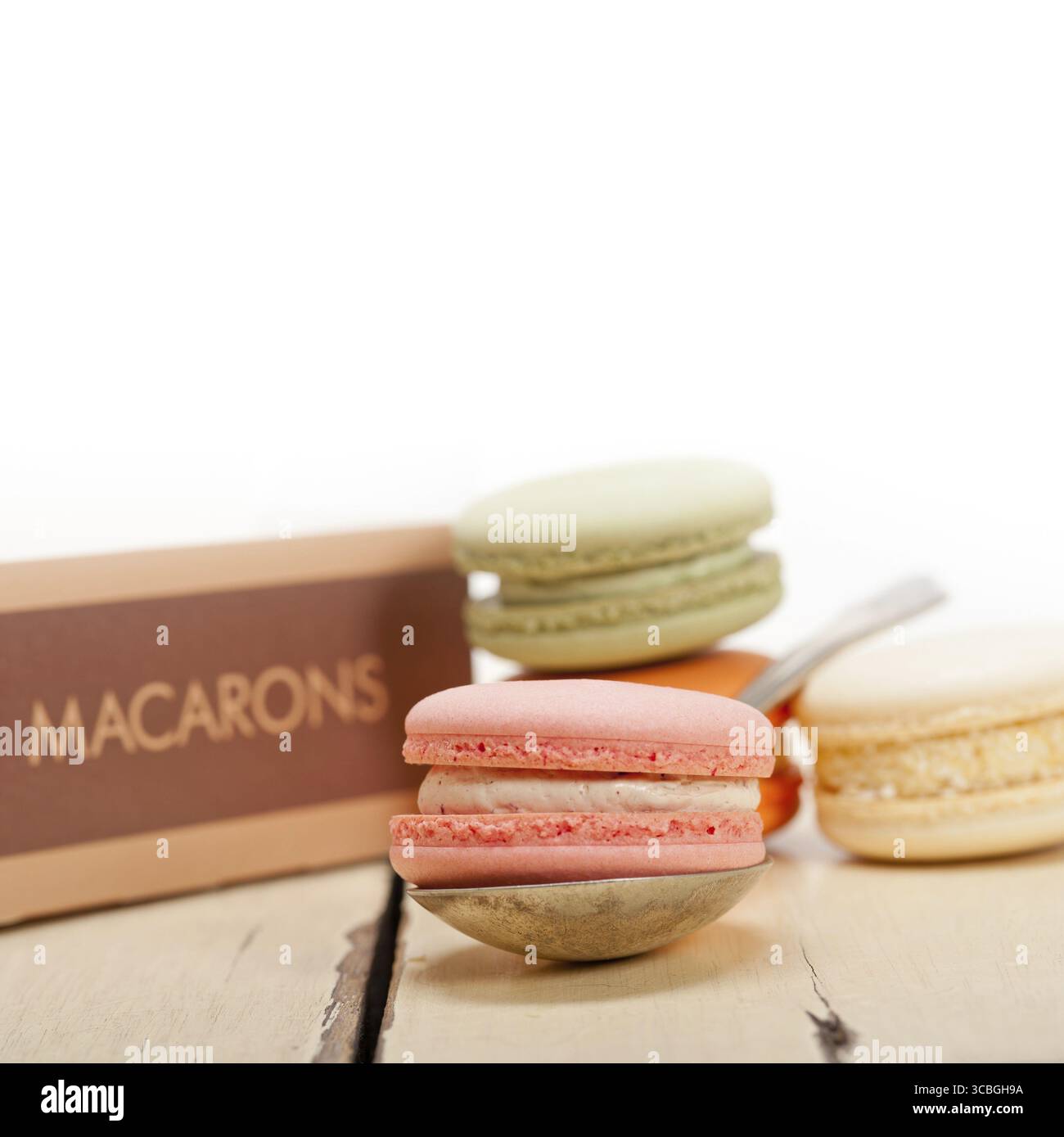 Macarons français colorés sur une table en bois rustique blanc Banque D'Images