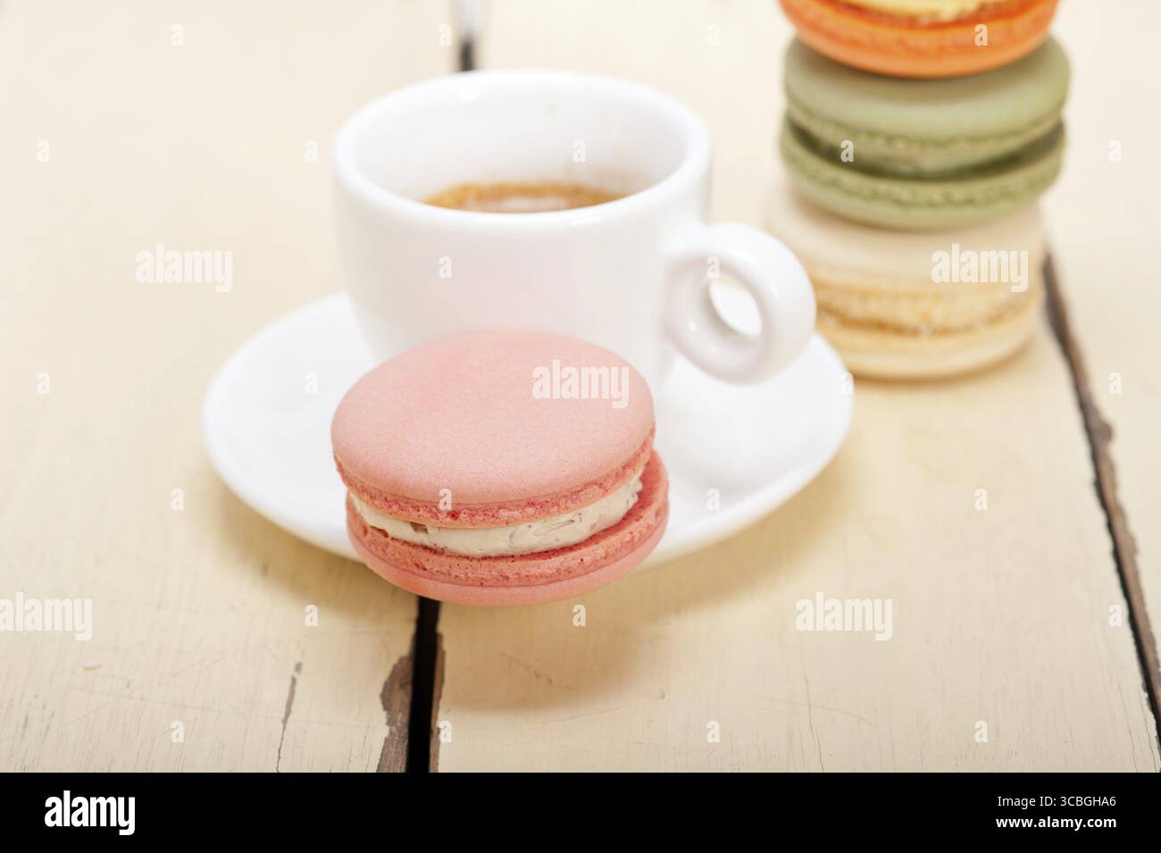 Macarons colorés avec café expresso sur table en bois blanc Banque D'Images