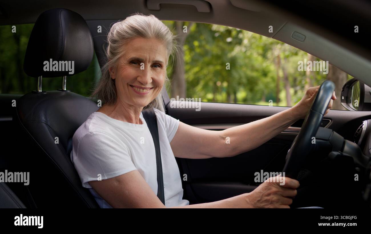 Heureux souriant caucasien mature senior femme propriétaire d'automobile femme grand-mère conducteur d'automobile assis à l'intérieur de la nouvelle voiture électrique moderne Banque D'Images