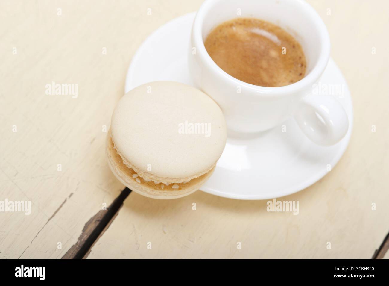 Macarons colorés avec café expresso sur table en bois blanc Banque D'Images