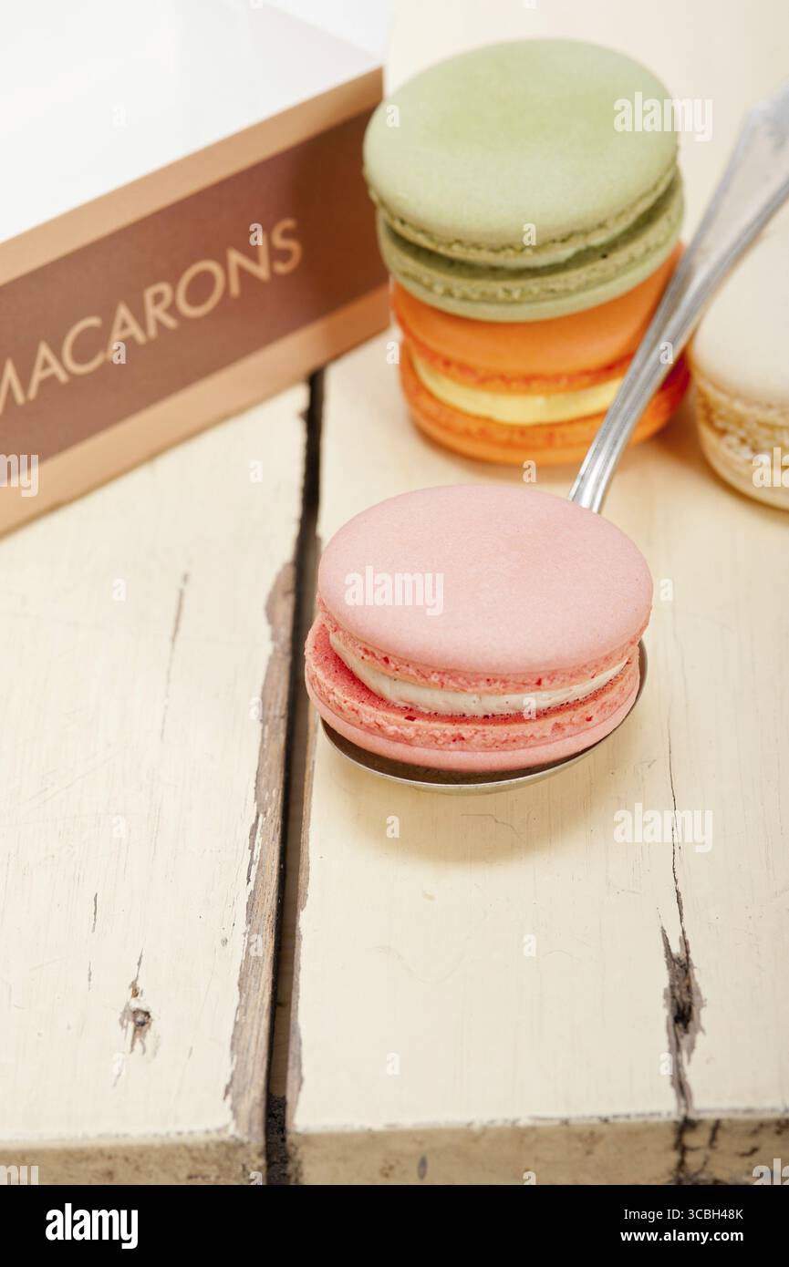 Macarons français colorés sur une table en bois rustique blanc Banque D'Images