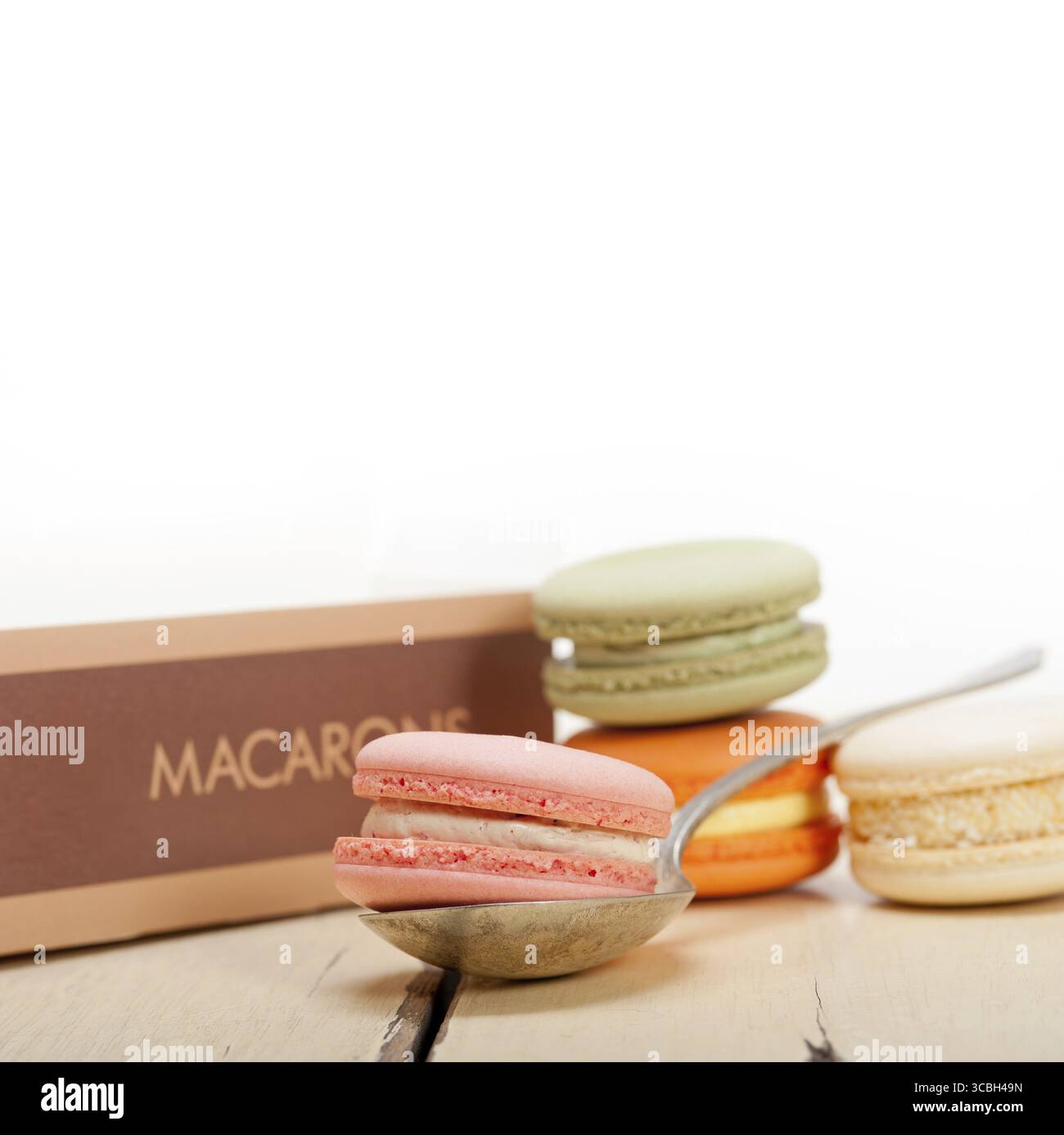 Macarons français colorés sur une table en bois rustique blanc Banque D'Images