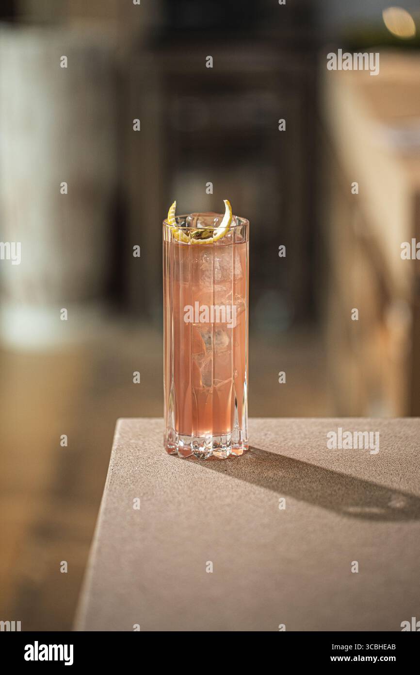 Cocktail rose dans un grand verre avec citron et glace Banque D'Images