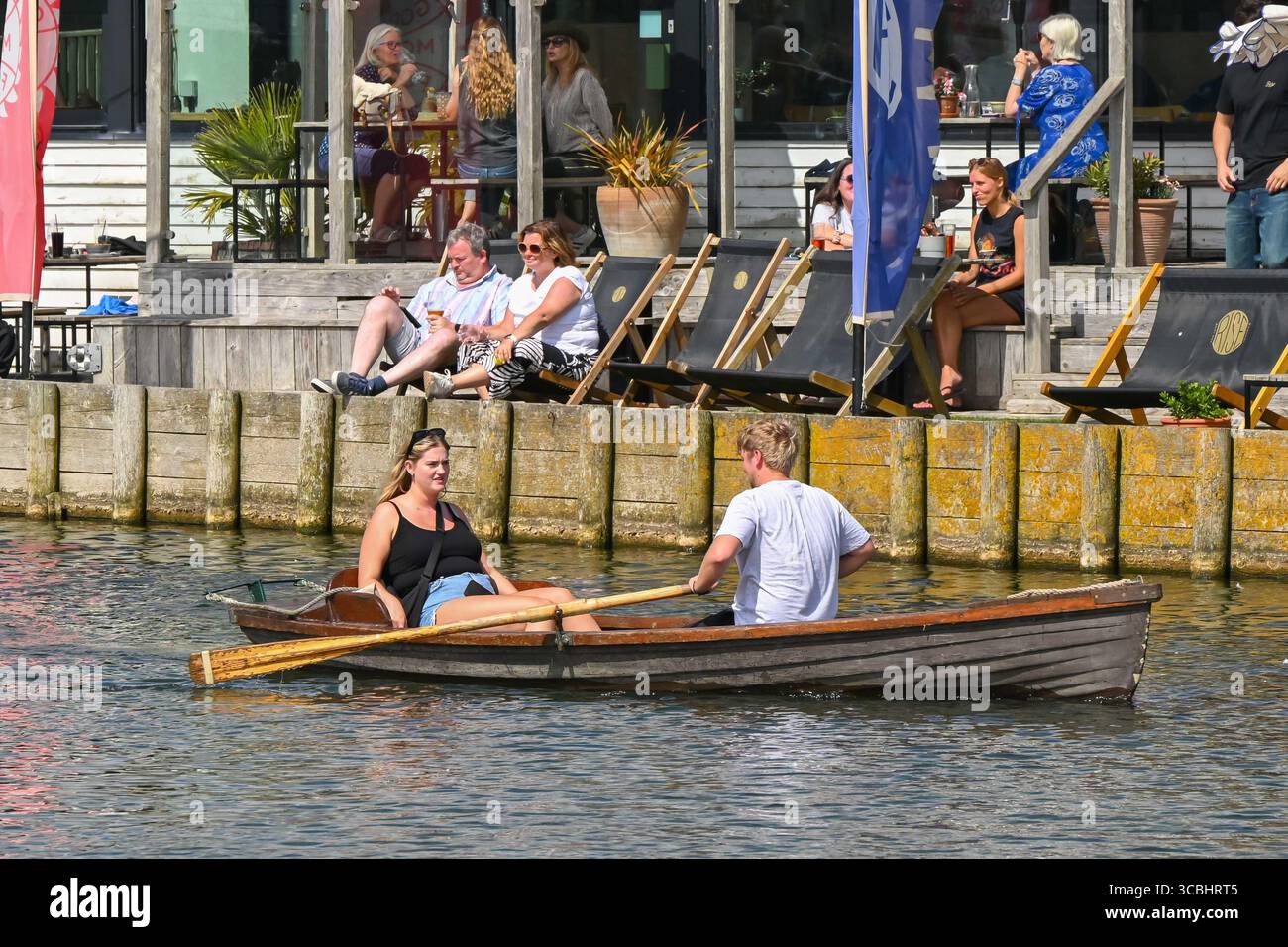 West Bay, Dorset, Royaume-Uni. 8 août 2025. Météo britannique. Les vacanciers ayant du plaisir à ramer un bateau le long de la rivière Brit comme ils apprécient le soleil brûlant de l'après-midi à la station balnéaire de West Bay dans le Dorset pendant les vacances d'été. Crédit photo : Graham Hunt/Alamy Live News Banque D'Images