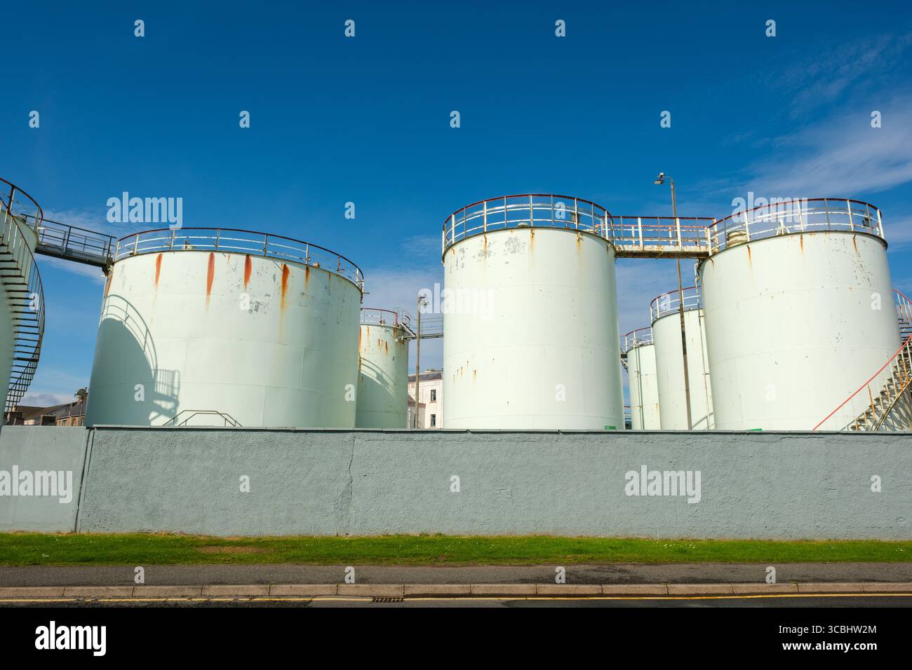 Des réservoirs de stockage d'huile industrielle avec des taches de rouille bordent le périmètre d'un dépôt à Stornoway, en Écosse. Banque D'Images