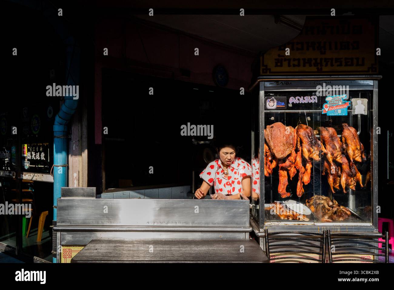14 février 2023, Bangkok, Thaïlande : une vendeuse de nourriture de rue portant une blouse avec des coeurs de Saint-Valentin prépare son stand pour les clients dans le soleil de l'après-midi. (Crédit image : © Matt Hunt/ZUMA Press Wire) Banque D'Images
