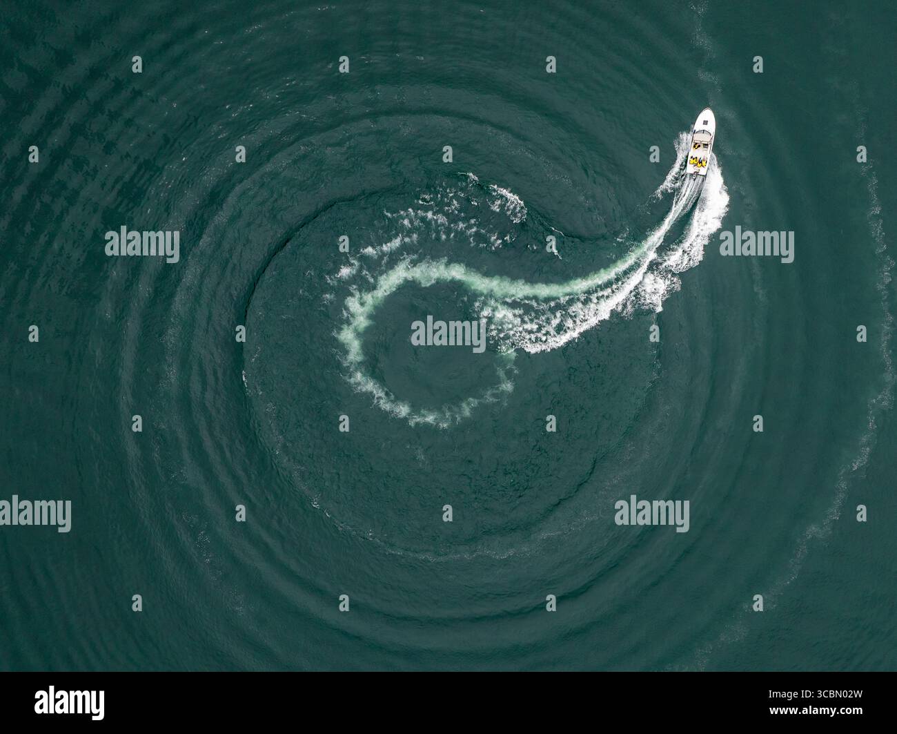Vue aérienne d'un bateau traçant un chemin en spirale sur la surface sombre de l'eau, laissant une traînée d'écume blanche dans son sillage, le lac Kawagushi, Japon. Banque D'Images