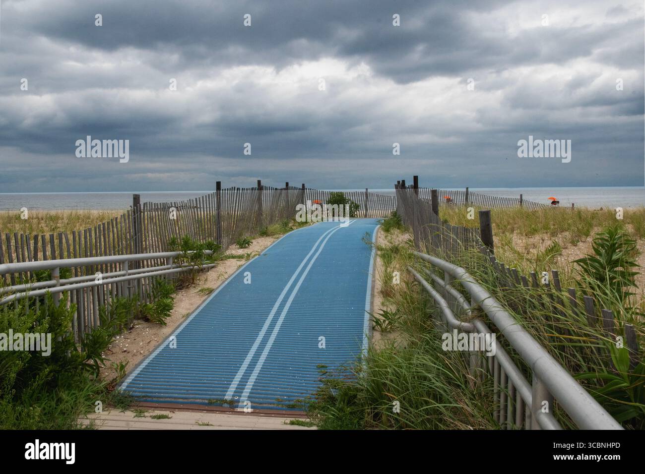 Promenade de Rockaway Beach avec nuages sombres et entrée de plage Banque D'Images