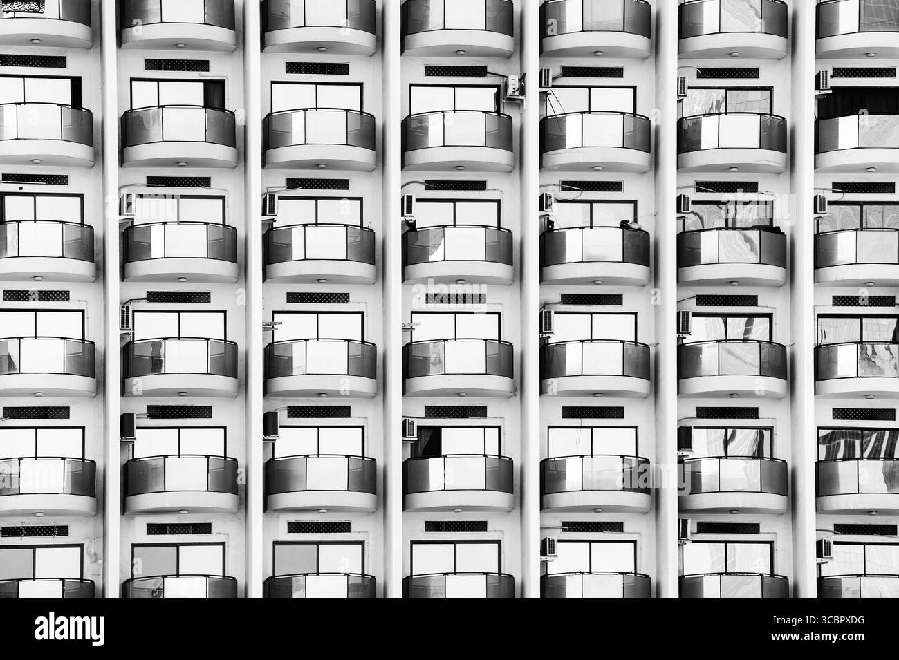 Motif symétrique noir et blanc de balcons d'appartements modernes avec balustrades en verre, créant un design urbain architectural. Banque D'Images