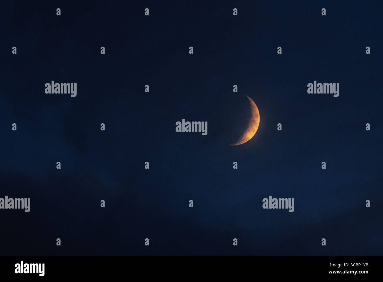 Nouvelle lune la lune illuminée par le soleil en orange au crépuscule sur le ciel bleu de motte Banque D'Images