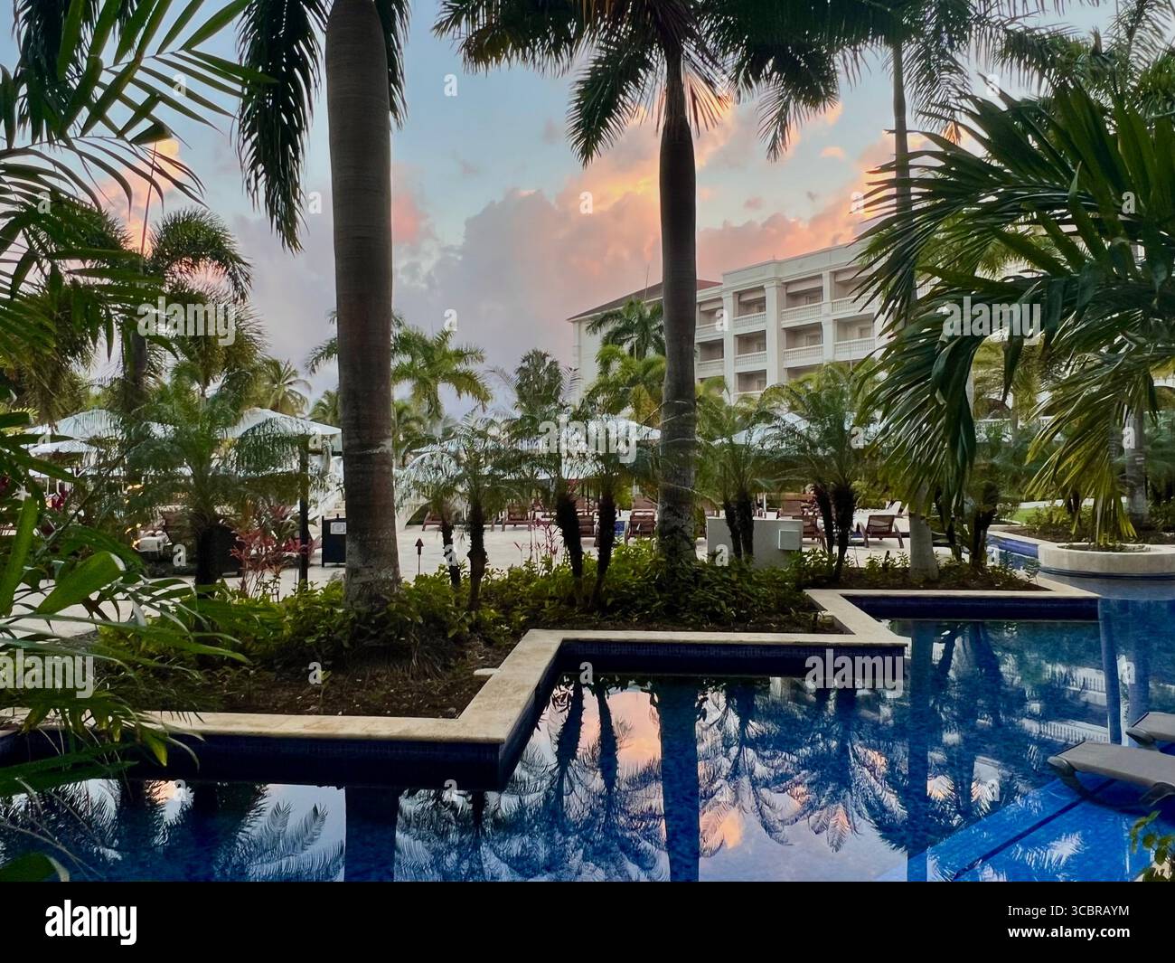Douce lueur d'un coucher de soleil reflétant dans une piscine d'un complexe hôtelier à Montego Bay, Jamaïque - Image de stock capturée avec un smartphone