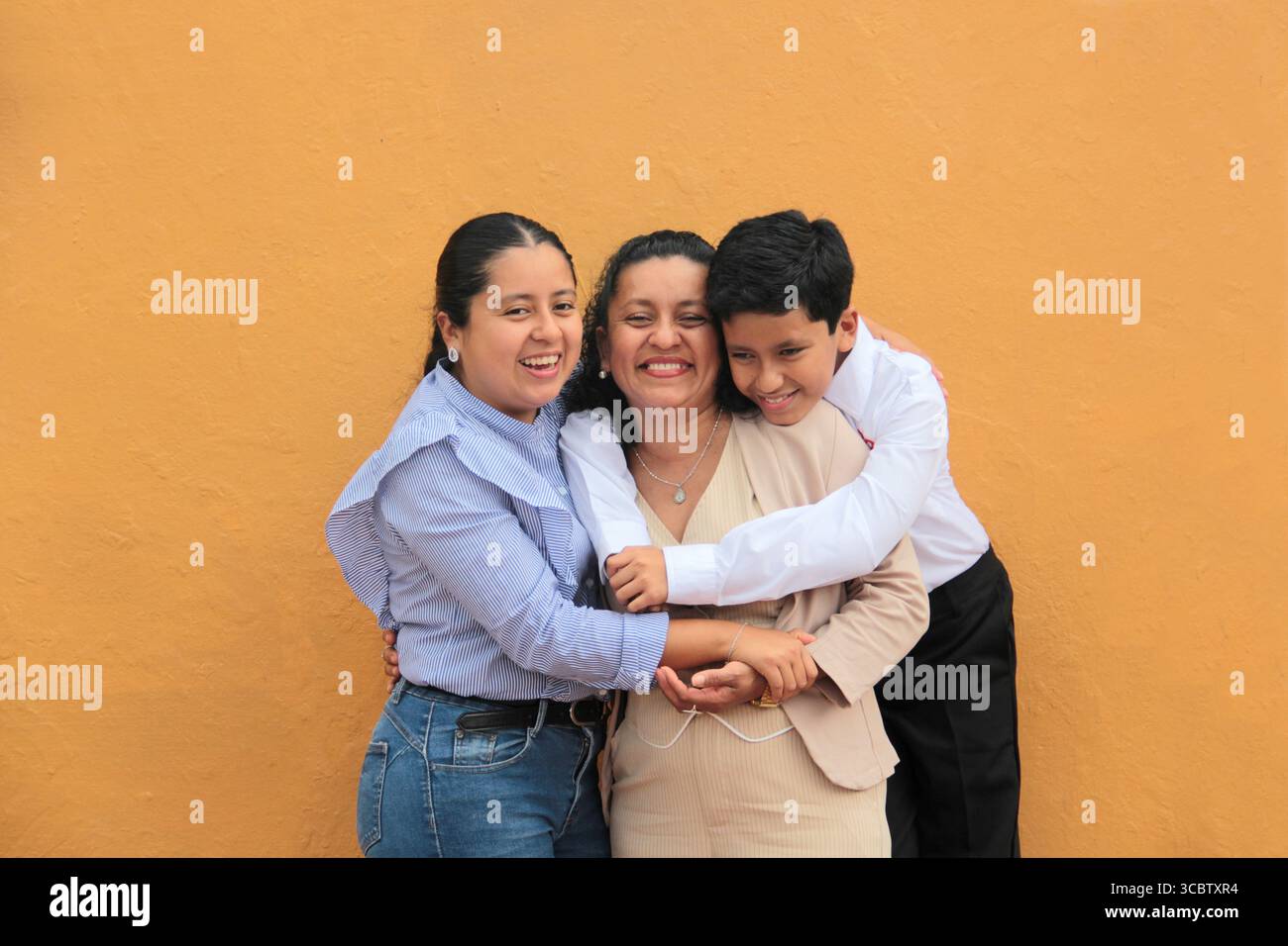 La mère, la fille et le fils latino-américains à la peau foncée montrent leur amour avec des câlins et célèbrent la fête des mères avec leur famille Banque D'Images La mère, la fille et le fils latino-américains à la peau foncée montrent leur amour avec des câlins et célèbrent la fête des mères avec leur famille Banque D'Images