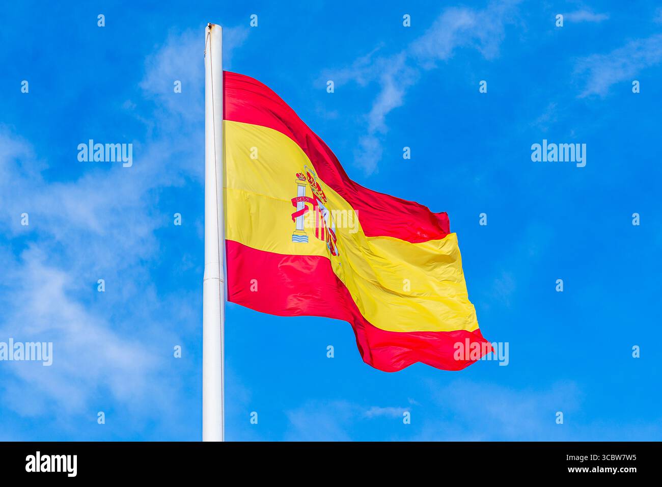Drapeau national de l'Espagne volant dans le vent ; drapeau national rouge et jaune sur fond de ciel bleu Banque D'Images