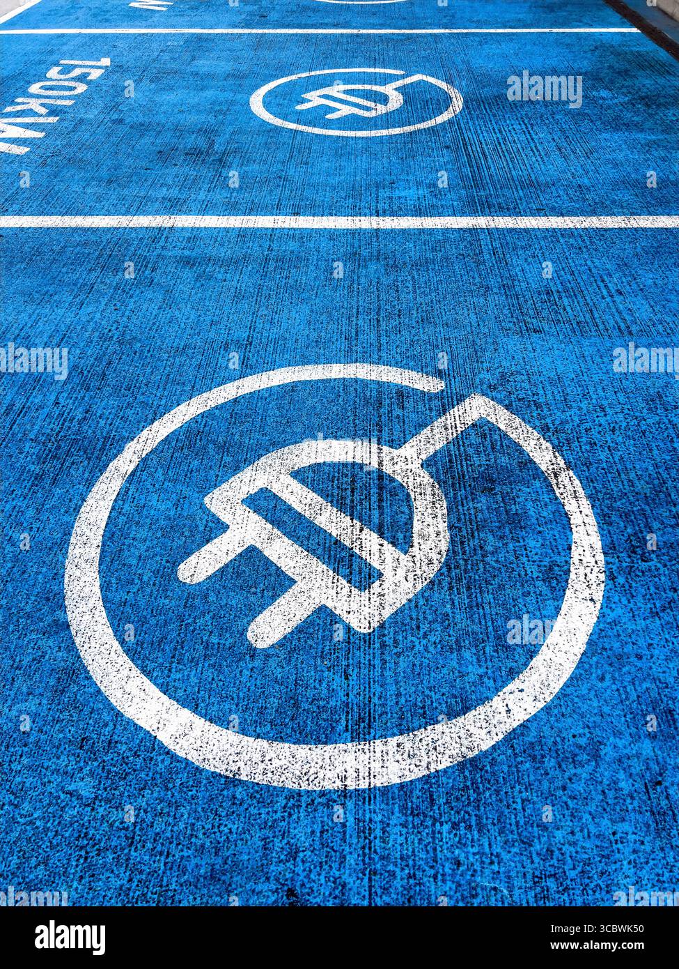 Vue aérienne d'une piste bleue de station de recharge de voiture électrique avec graphique de prise et signalisation de 150 kW sur une piste de garage Banque D'Images
