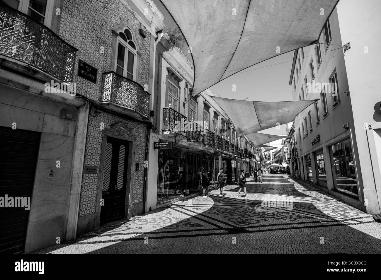 Faro, Algarve, Portugal – 2025.06.28 Une rue piétonne décorative avec des tuiles traditionnelles portugaises et des parasols, bordée de boutiques et bui historique Banque D'Images