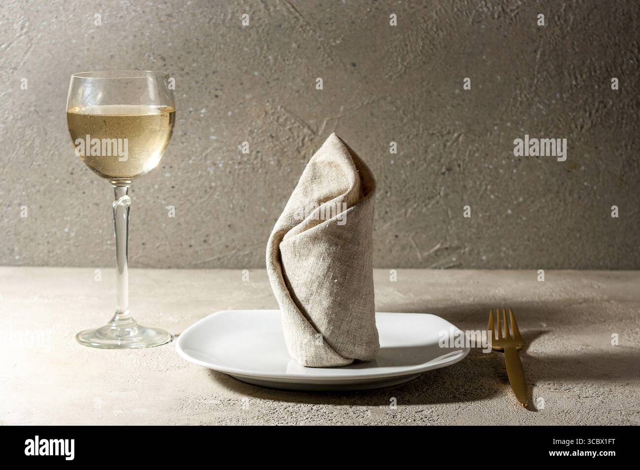 Assiette, serviette, fourchette, verre pour vin blanc sur la table Banque D'Images