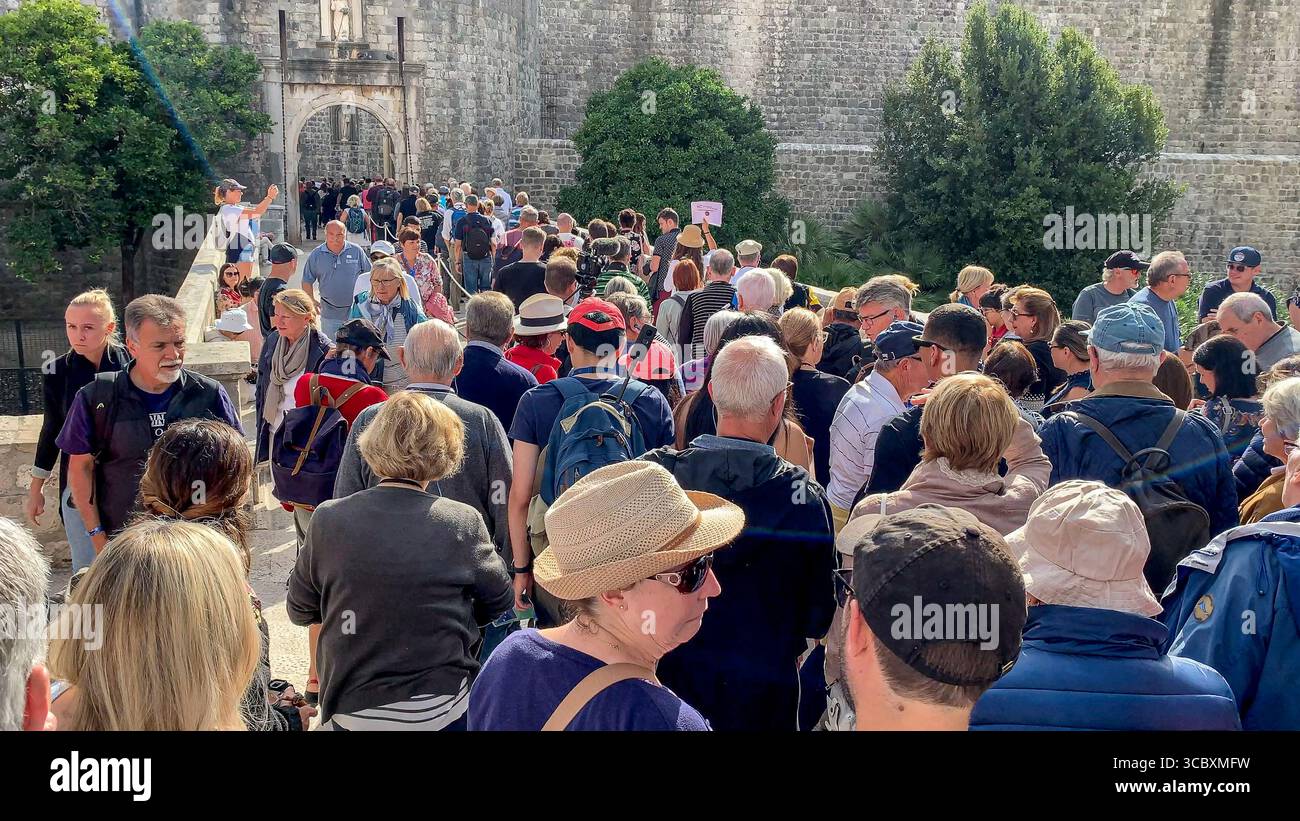 Dubrovnik, Croatie. Août 09,2025. Une foule de touristes se rassemble à l'entrée des remparts fortifiés de la vieille ville de Dubrovnik. Au premier plan, une femme grimace dans la surprise devant la longue file d'attente à venir. Depuis 2017, la ville la plus célèbre de Croatie, également connue pour sa réputation de « ville la plus surpeuplée du monde », a mis en œuvre de nombreuses mesures pour faire face à l'afflux de touristes, y compris des efforts pour organiser les flux de visiteurs en étalant les créneaux horaires de visite pour les principaux types de tourisme : passagers de bateaux de croisière, groupes de voyages en autocar et touristes séjournant dans les hébergements de la ville. Crédit : Kevin Izorce / Alamy Live News Banque D'Images