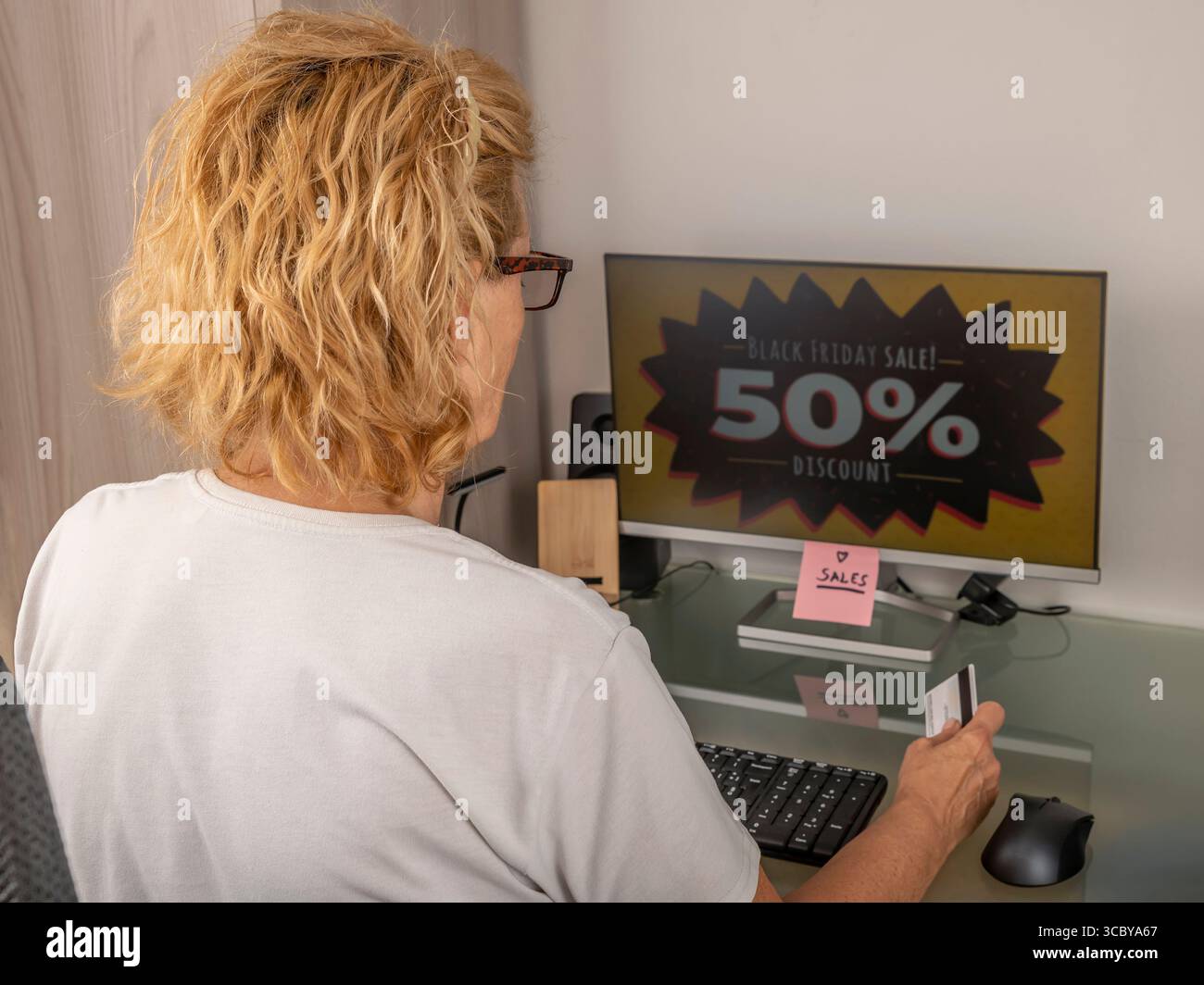Une femme blonde profite des réductions du Black Friday pour trouver de bonnes affaires en ligne Banque D'Images