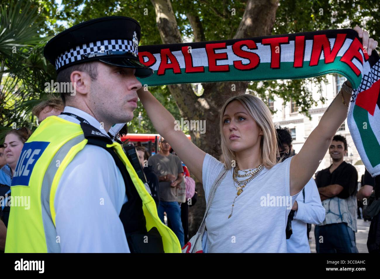 Une femme avec une écharpe palestinienne regarde directement un policier présent alors qu'ils arrêtent des manifestants pacifiques qui s'opposent au génocide et soutiennent le groupe d'action directe interdit Palestine action et qui sont venus sur la place du Parlement en toute connaissance de cause, ils seraient arrêtés et risqueraient d'être condamnés à de longues peines de prison pour leur opposition à la crise humanitaire en cours à Gaza le 9 août 2025 à Londres, Royaume-Uni. De nombreux manifestants ont également manifesté leur soutien aux personnes arrêtées pour avoir soutenu Palestine action que le gouvernement britannique a récemment interdite comme organisation terroriste. Metropolita Banque D'Images