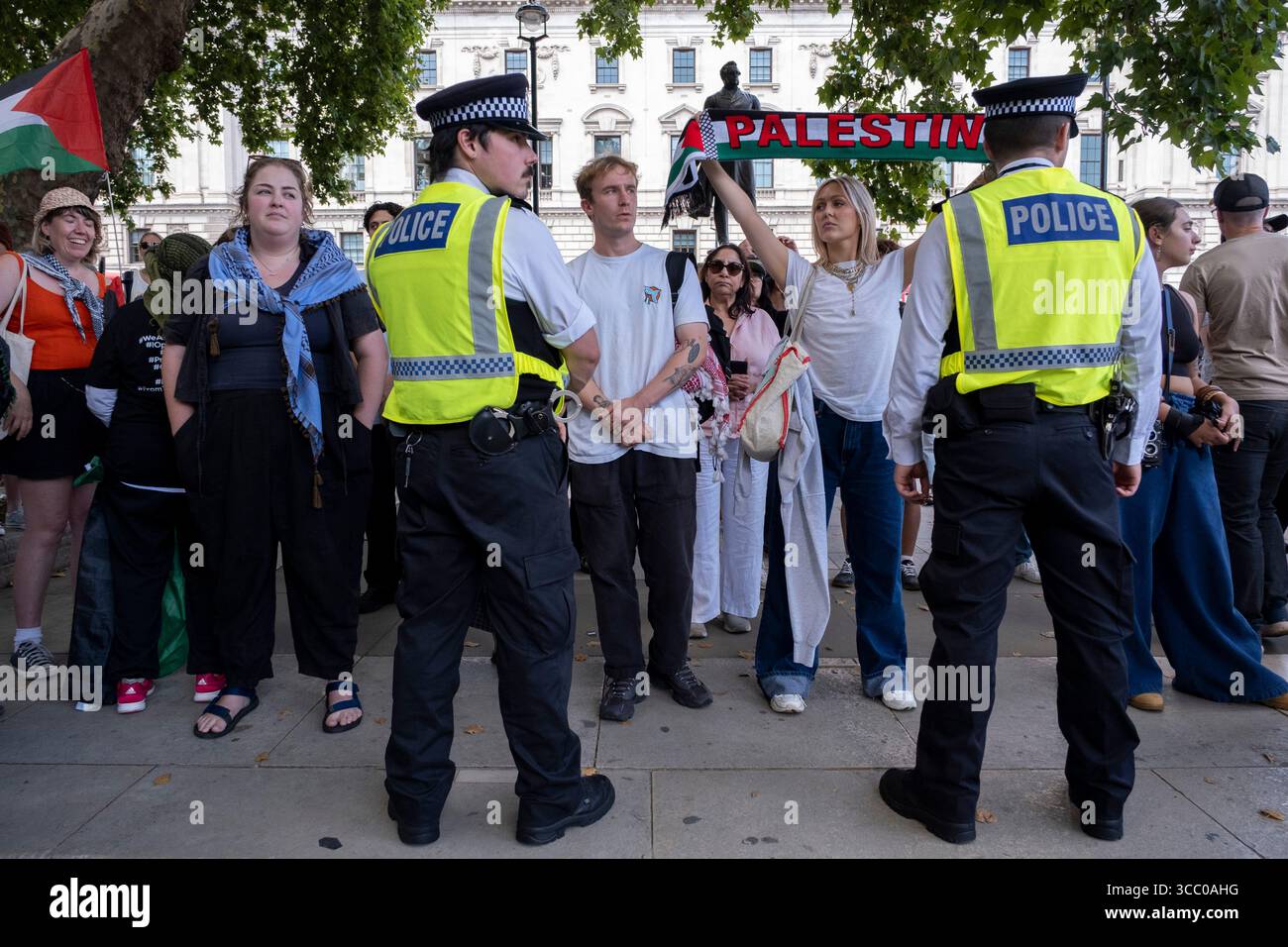 Une femme avec une écharpe palestinienne regarde directement un policier présent alors qu'ils arrêtent des manifestants pacifiques qui s'opposent au génocide et soutiennent le groupe d'action directe interdit Palestine action et qui sont venus sur la place du Parlement en toute connaissance de cause, ils seraient arrêtés et risqueraient d'être condamnés à de longues peines de prison pour leur opposition à la crise humanitaire en cours à Gaza le 9 août 2025 à Londres, Royaume-Uni. De nombreux manifestants ont également manifesté leur soutien aux personnes arrêtées pour avoir soutenu Palestine action que le gouvernement britannique a récemment interdite comme organisation terroriste. Metropolita Banque D'Images