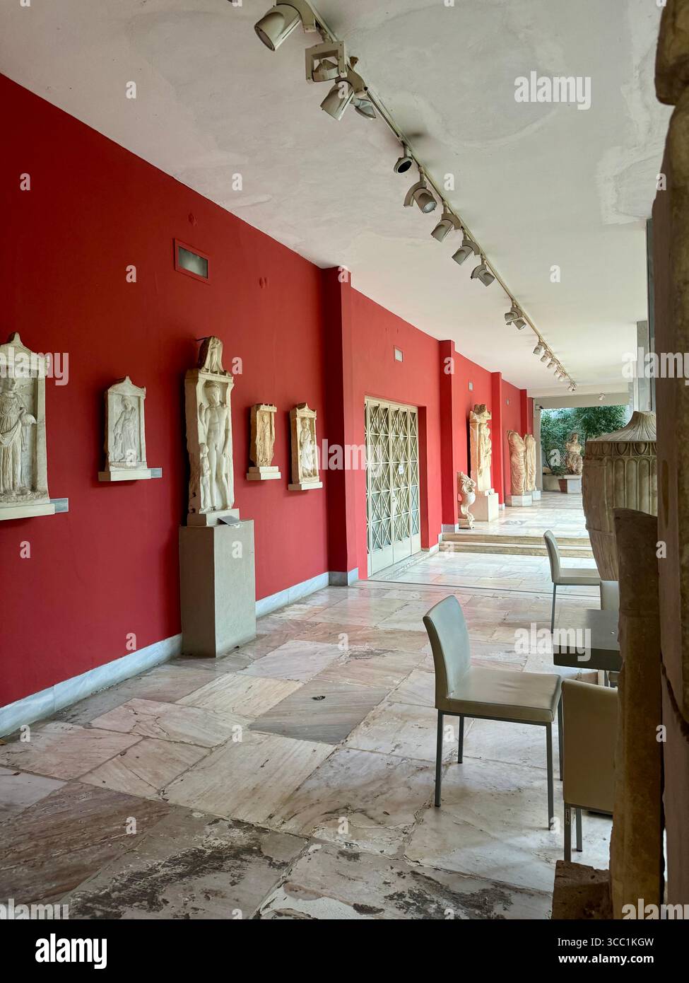 Statues et objets en pierre exposés le long d'un couloir rouge dans le Musée archéologique national d'Athènes, Grèce. Banque D'Images