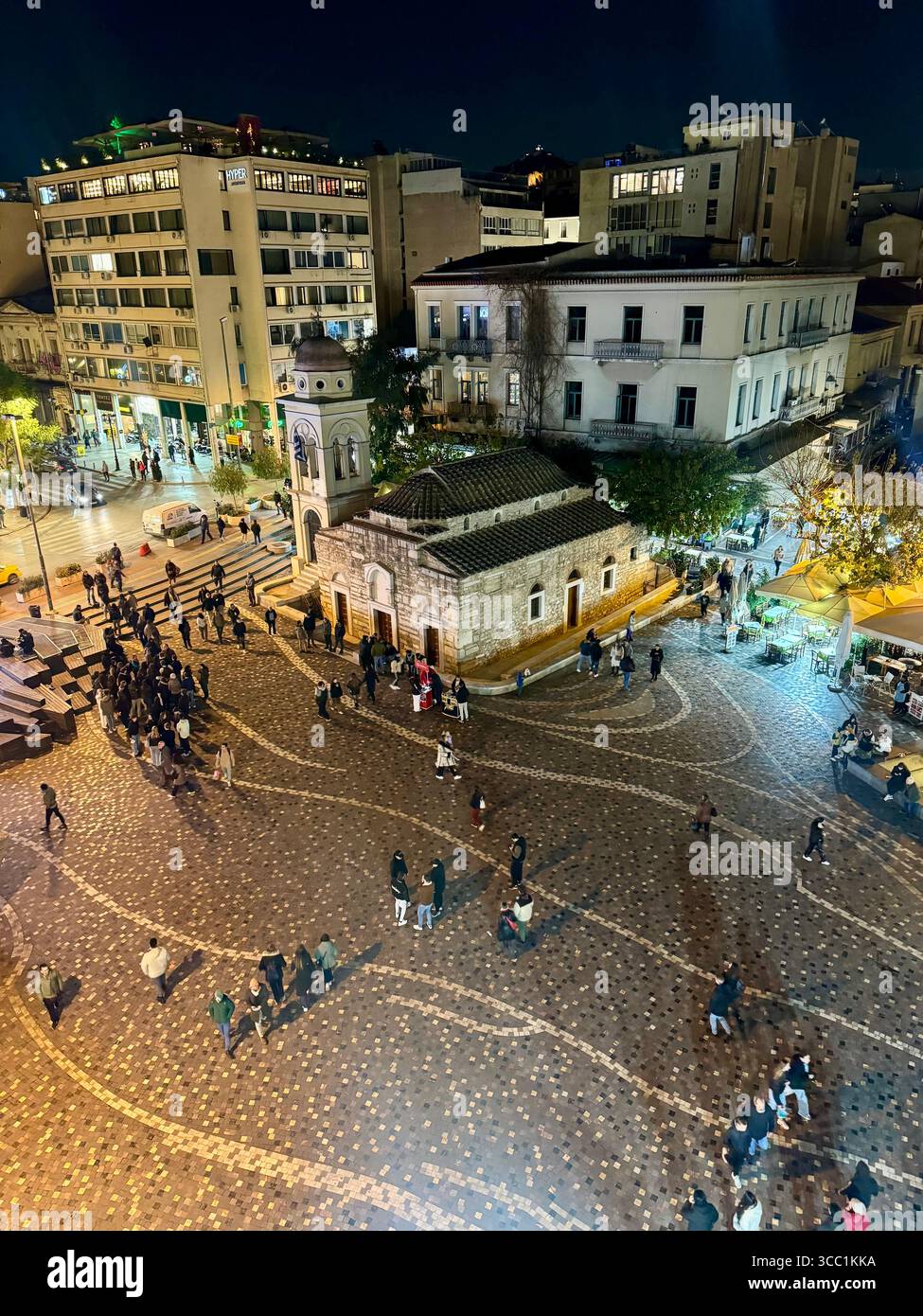 Vue nocturne de la place Monastiraki à Athènes, Grèce, avec une vieille église, des rues illuminées et des gens marchant. Banque D'Images