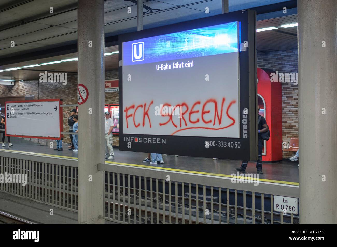 Ein Werbe- und Nachrichtenscreen in der Kšlner U-Bahn-Station Hansaring, mit dem Graffiti FCK Screens beschmiert. Die Schmiererei richtet sich offensi Banque D'Images