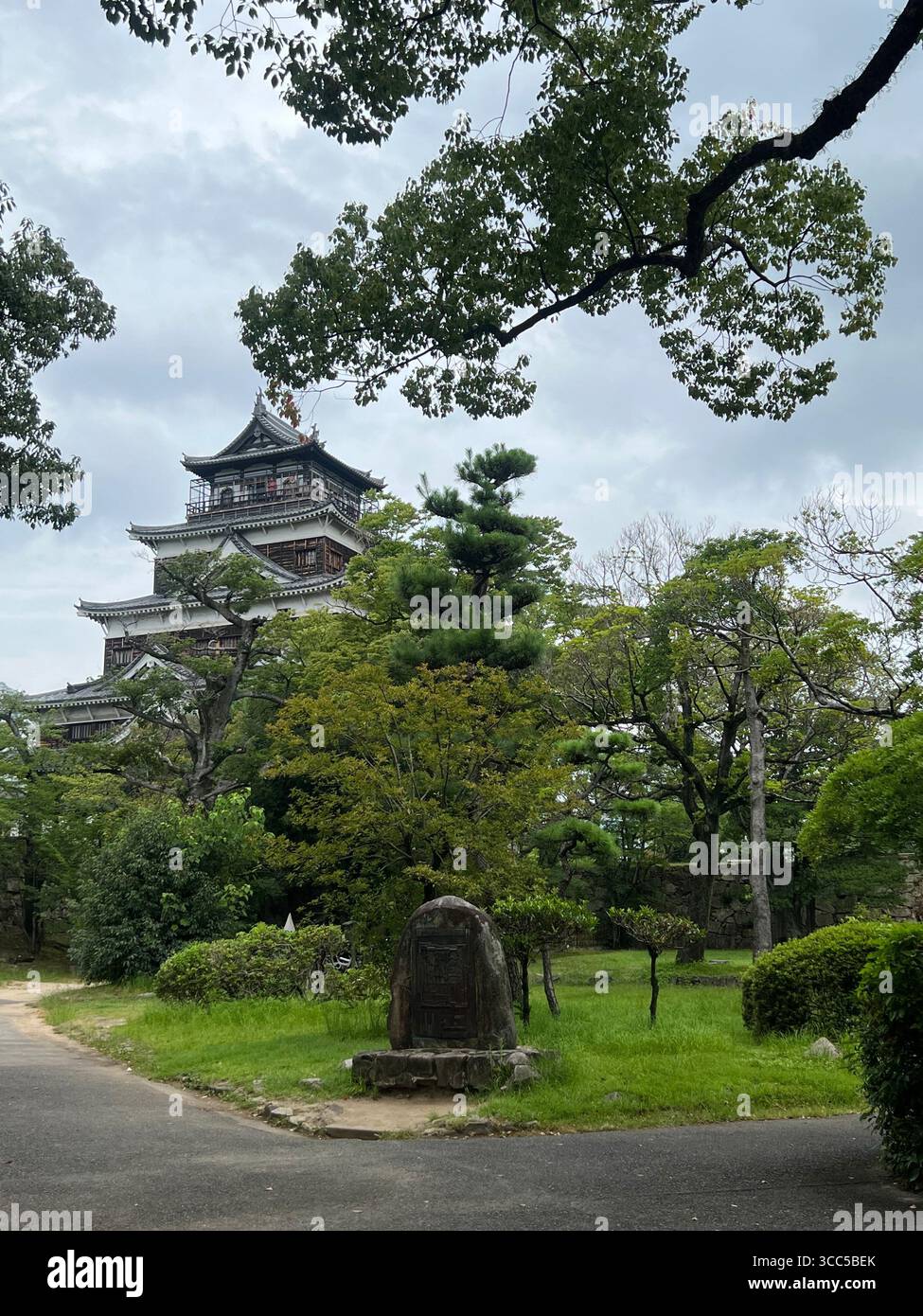 Château d'Hiroshima au Japon, entouré d'arbres verdoyants par une journée nuageuse. Banque D'Images