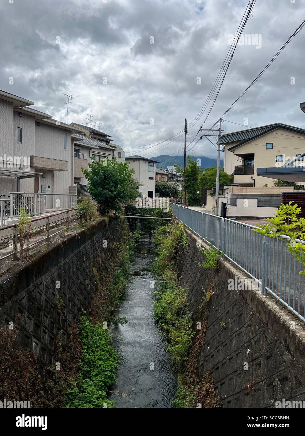 Une porte torii rouge menant à une petite cour sanctuaire à Kyoto, au Japon, entourée de lanternes en pierre et offrant des pierres. Banque D'Images