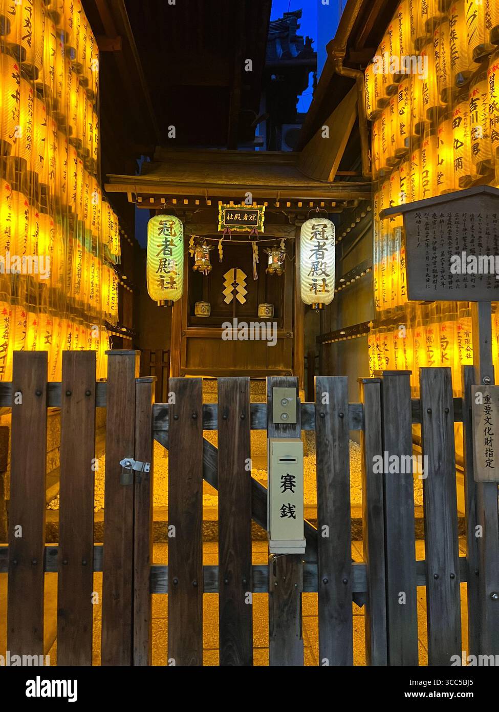 Lanternes illuminées et porte en bois d'un sanctuaire japonais traditionnel la nuit à Kyoto, Japon Banque D'Images