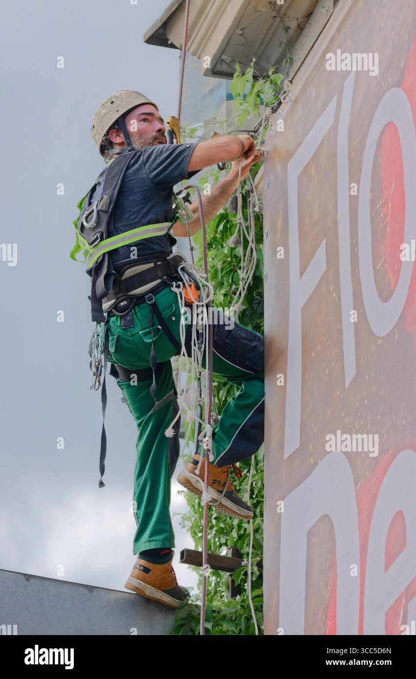 Travailleur réparant des appareils de télécommunication sur un mur de bâtiment Banque D'Images