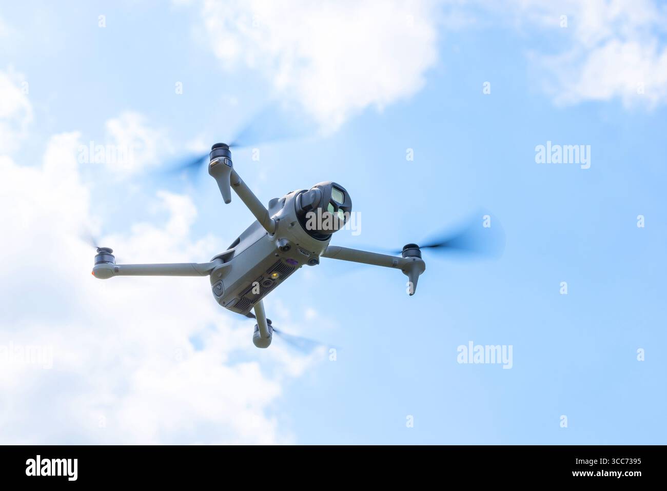 Gros plan vue de dessous d'un drone volant avec la caméra orientée vers l'avant sous le ciel bleu Banque D'Images